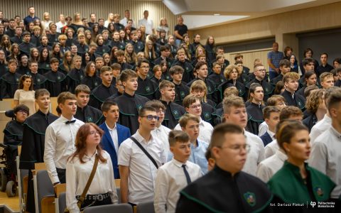 duża grupa młodzieży stoi w auli