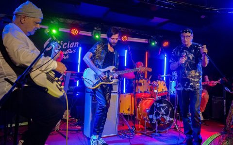 trzech gitarzystów na scenie